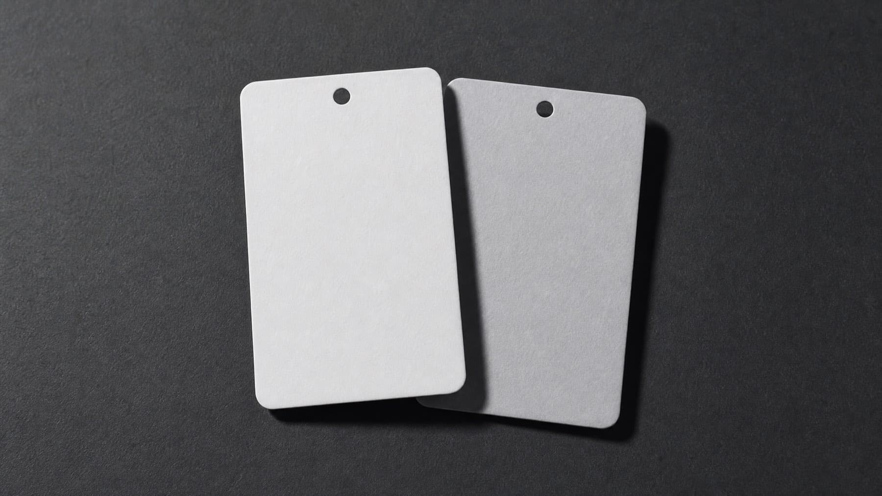 Two blank hangtags side by side on a dark surface