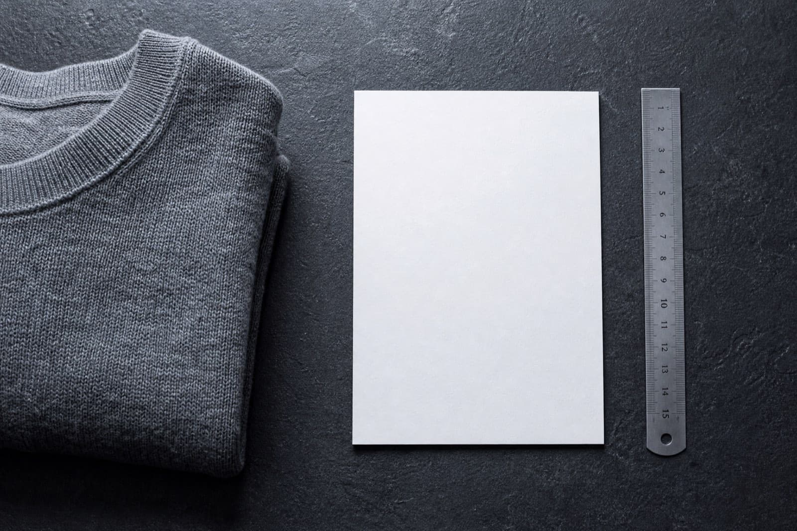 A blank card and a folded garment on a dark desk